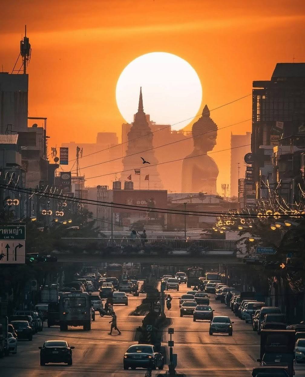 Silueta de un Buda gigante y una calle de Bangkok al atardecer
