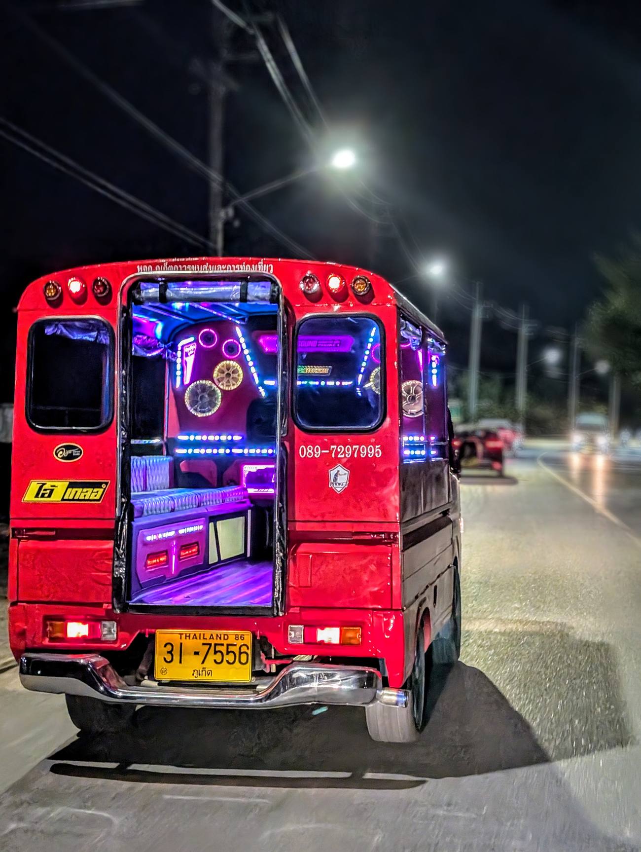 Transporte local nocturno decorado con luces en una calle de Tailandia