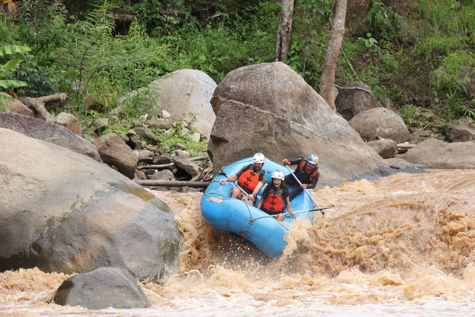 Balsa de rafting bajando unos rápidos de aguas embarradas cerca de Chiang Mai, con el equipo remando