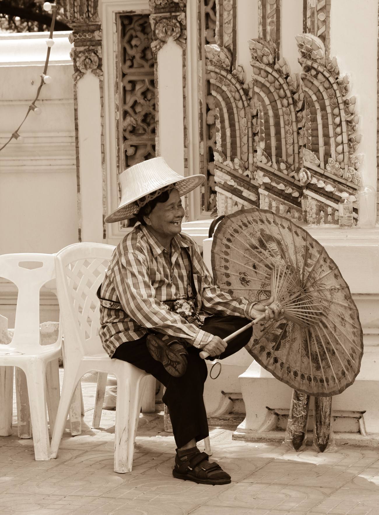 Mujer tailandesa sonriendo con un paraguas tradicional frente a un templo