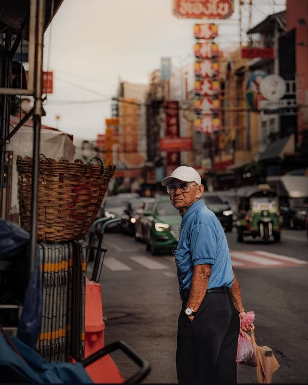 Hombre mayor en una calle del barrio chino de Bangkok, entre farolillos y puestos
